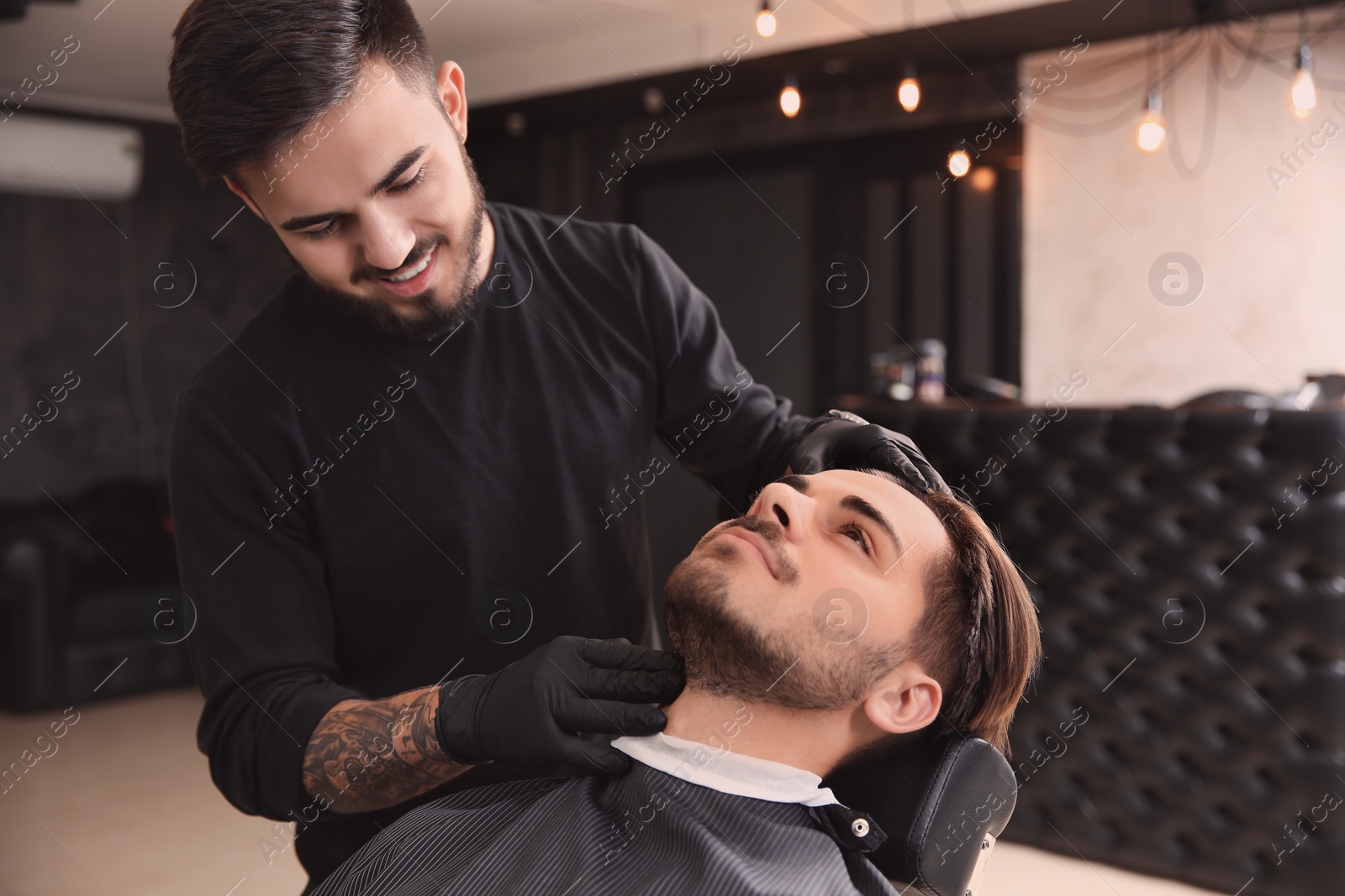 Photo of Professional hairdresser preparing client to shaving at barbershop