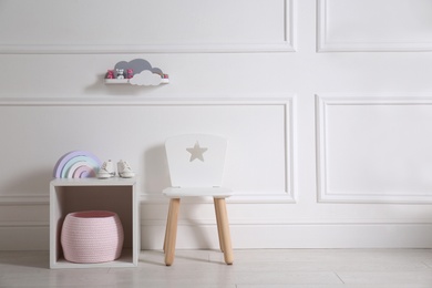 Modern child room interior with different accessories on stand near white wall. Space for text