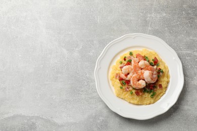 Photo of Plate with fresh tasty shrimps, bacon, grits, green onion and pepper on gray textured table, top view. Space for text