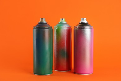 Used cans of spray paints on orange background