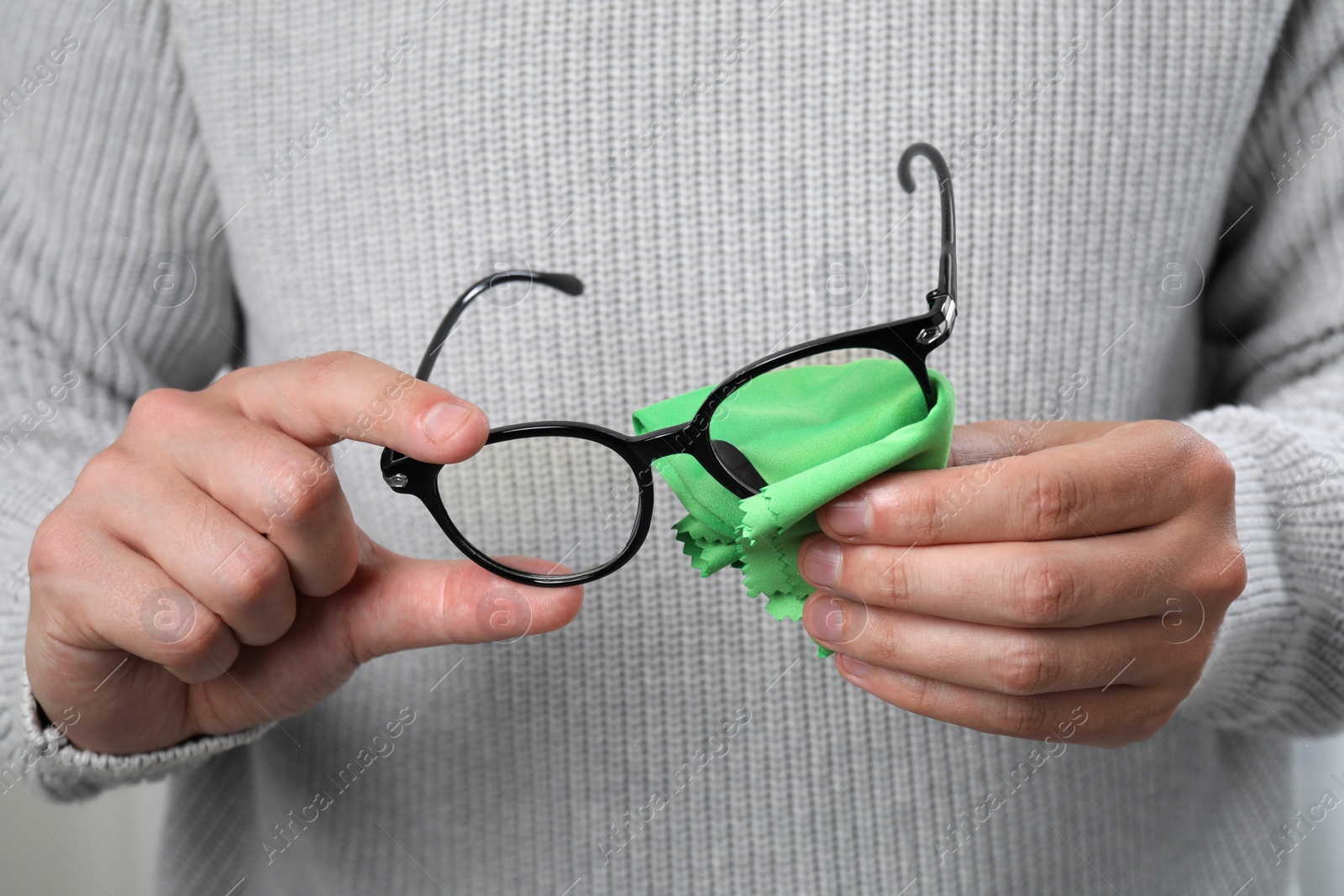 Photo of Man wiping glasses with microfiber cloth, closeup