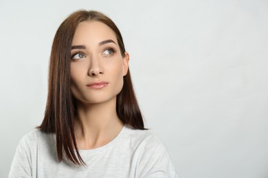 Photo of Portrait of pretty young woman with gorgeous chestnut hair on light background, space for text