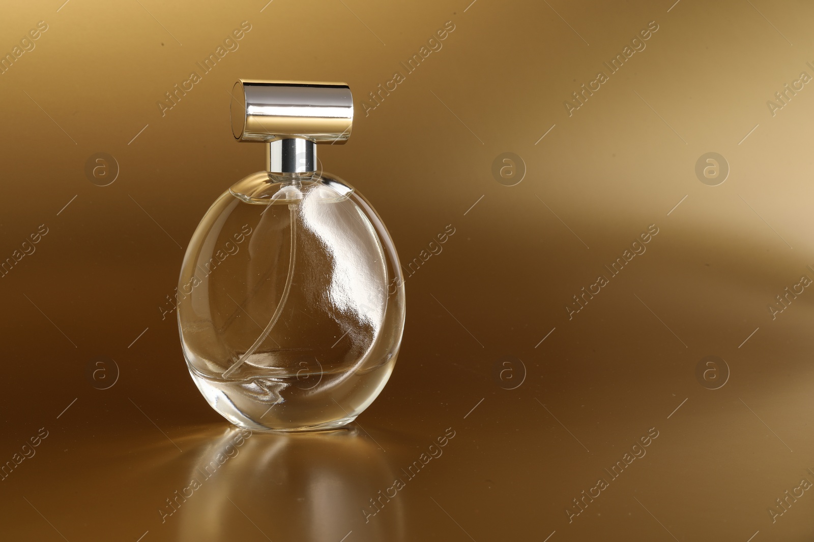 Photo of Luxury women's perfume. Sunlit glass bottle on golden background, space for text