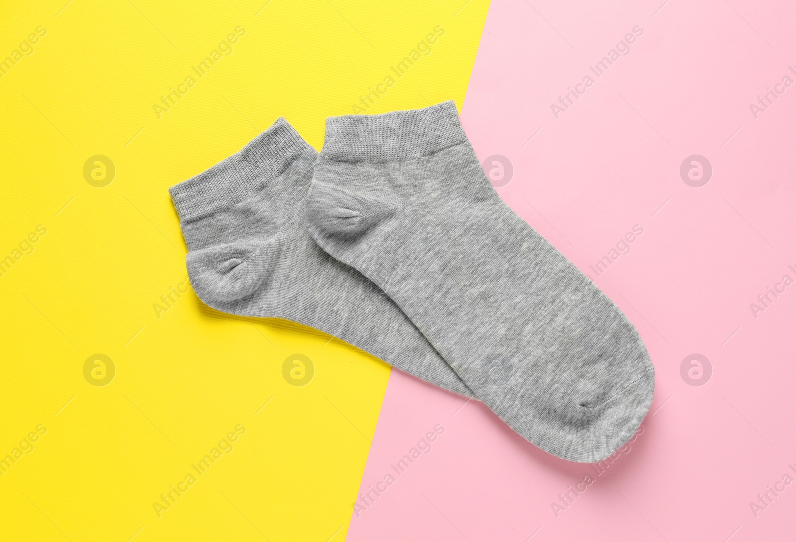 Photo of Pair of grey socks on colorful background, flat lay