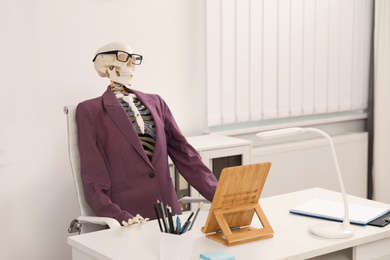 Human skeleton in suit at table in office
