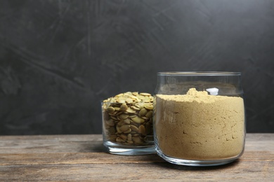 Bowl with pumpkin flour and seeds on wooden table. Space for text