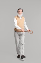 Senior man with walking cane on light gray background