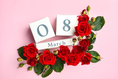 Wooden block calendar with date 8th of March and roses on pink background, flat lay. International Women's Day