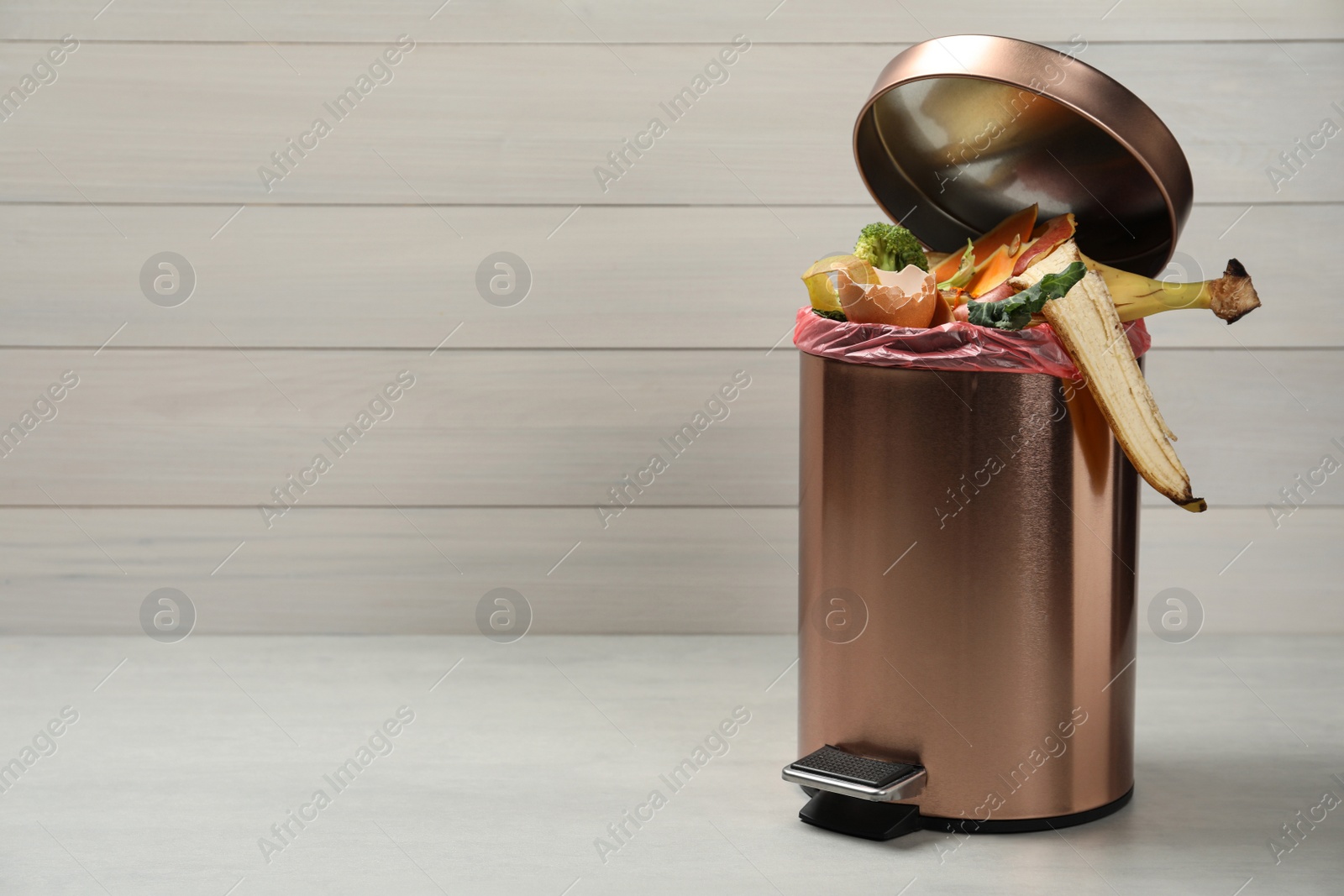 Photo of Trash bin with natural garbage on light background, space for text. Composting of organic waste