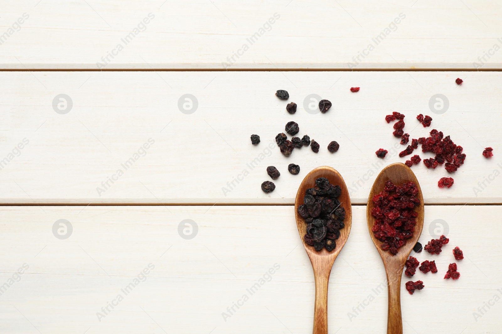 Photo of Dried red and black currant berries on white wooden table, flat lay. Space for text