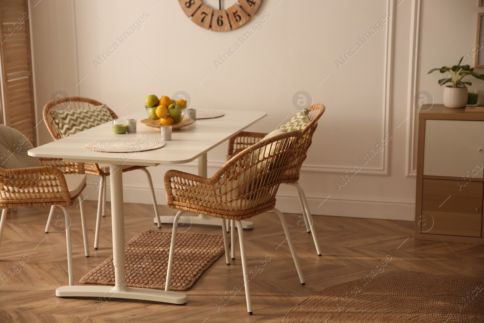 Photo of Stylish white dining table and wicker chairs in room. Interior design