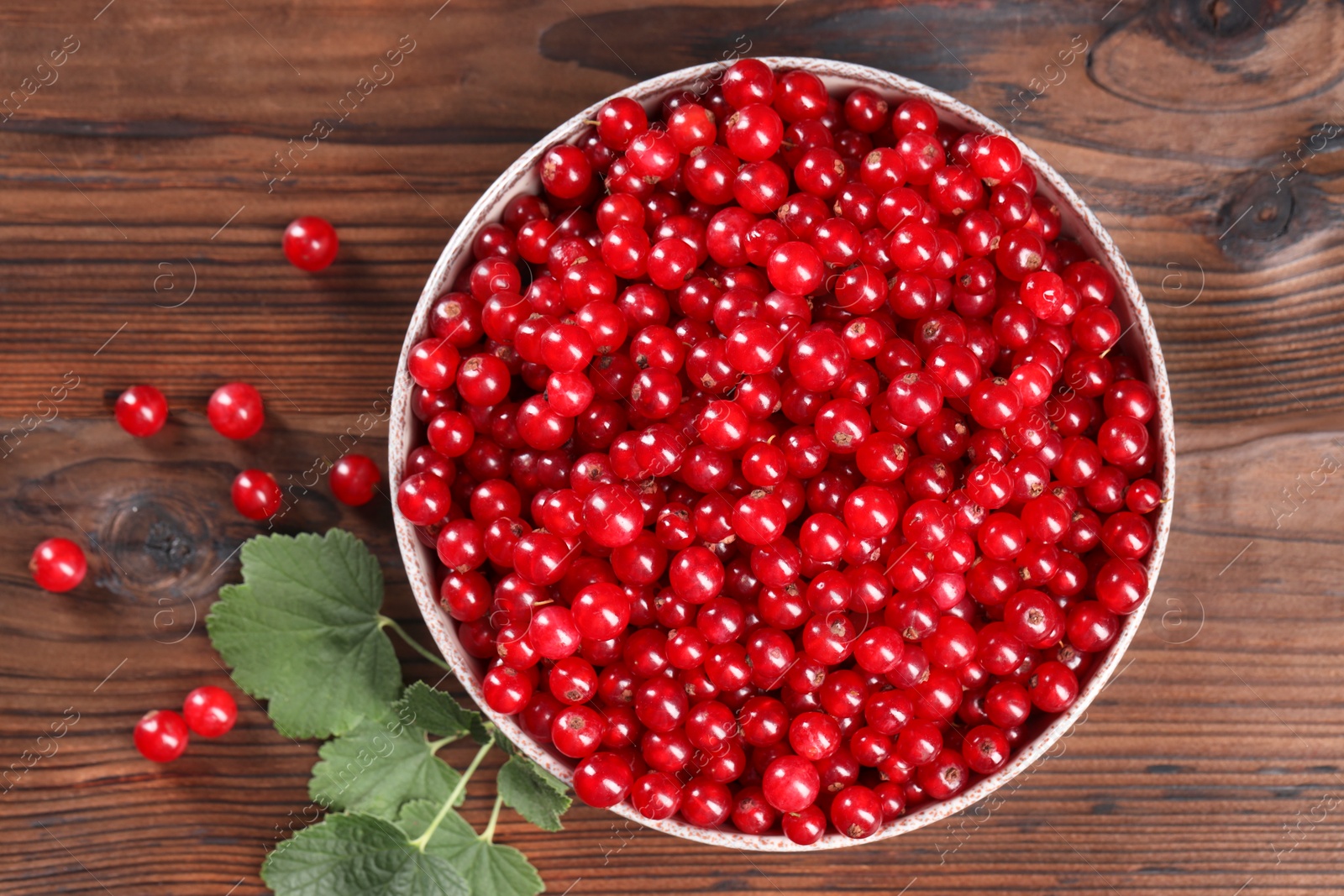 Photo of Ripe red currants and leaves on wooden table, flat lay