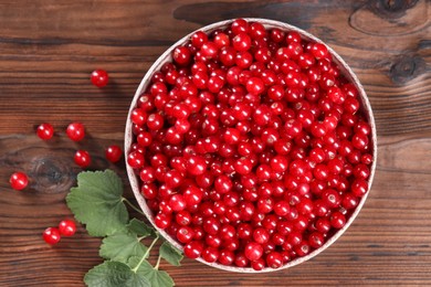 Photo of Ripe red currants and leaves on wooden table, flat lay