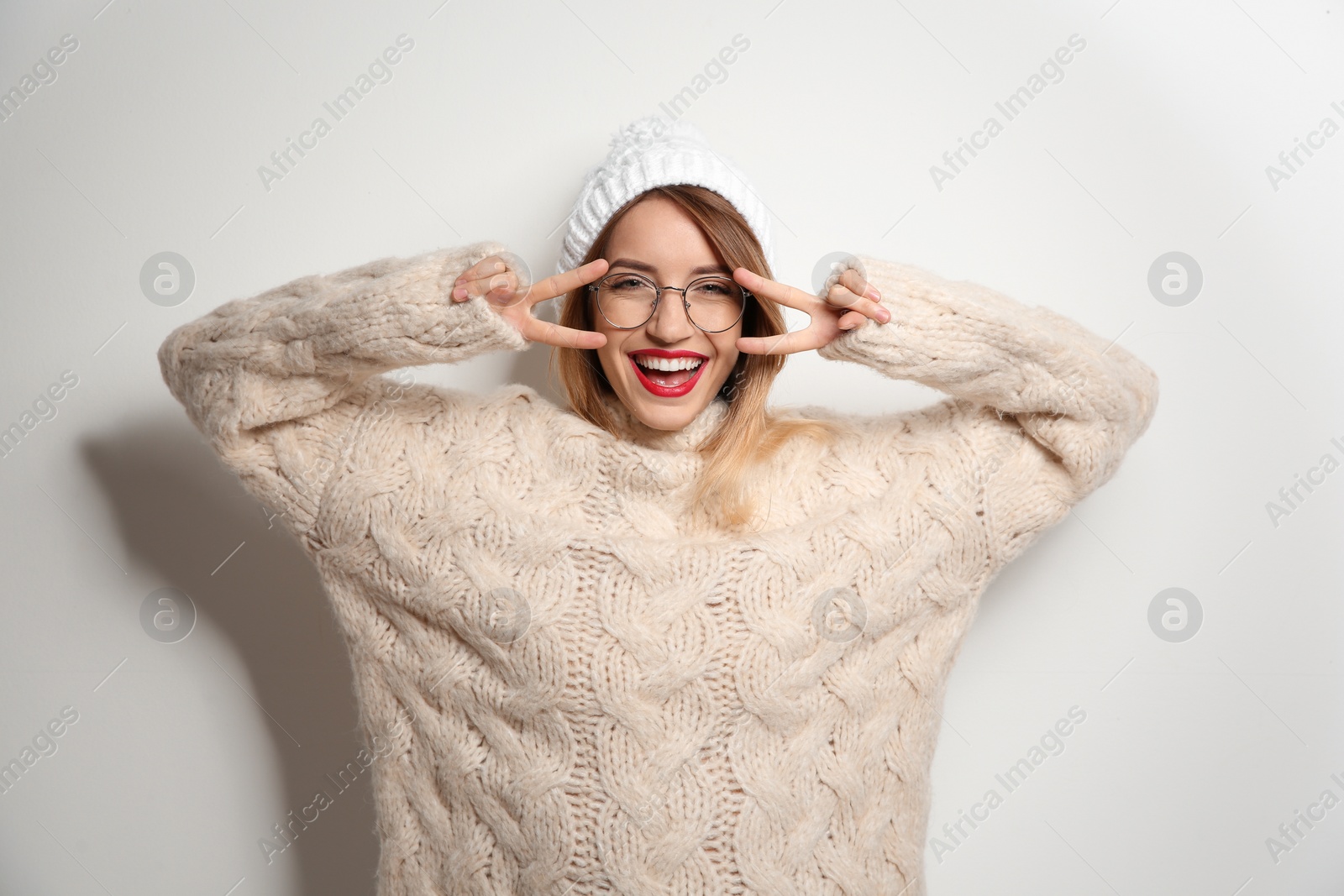 Photo of Beautiful young woman in warm sweater with hat on white background