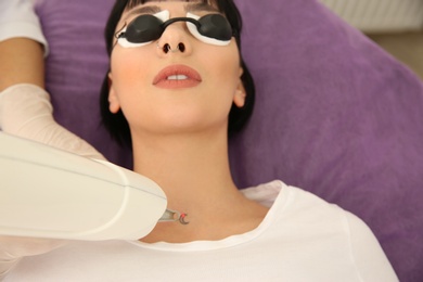 Photo of Young woman undergoing laser tattoo removal procedure in salon, above view