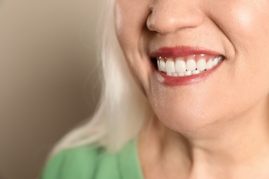 Photo of Smiling woman with perfect teeth on color background, closeup. Space for text