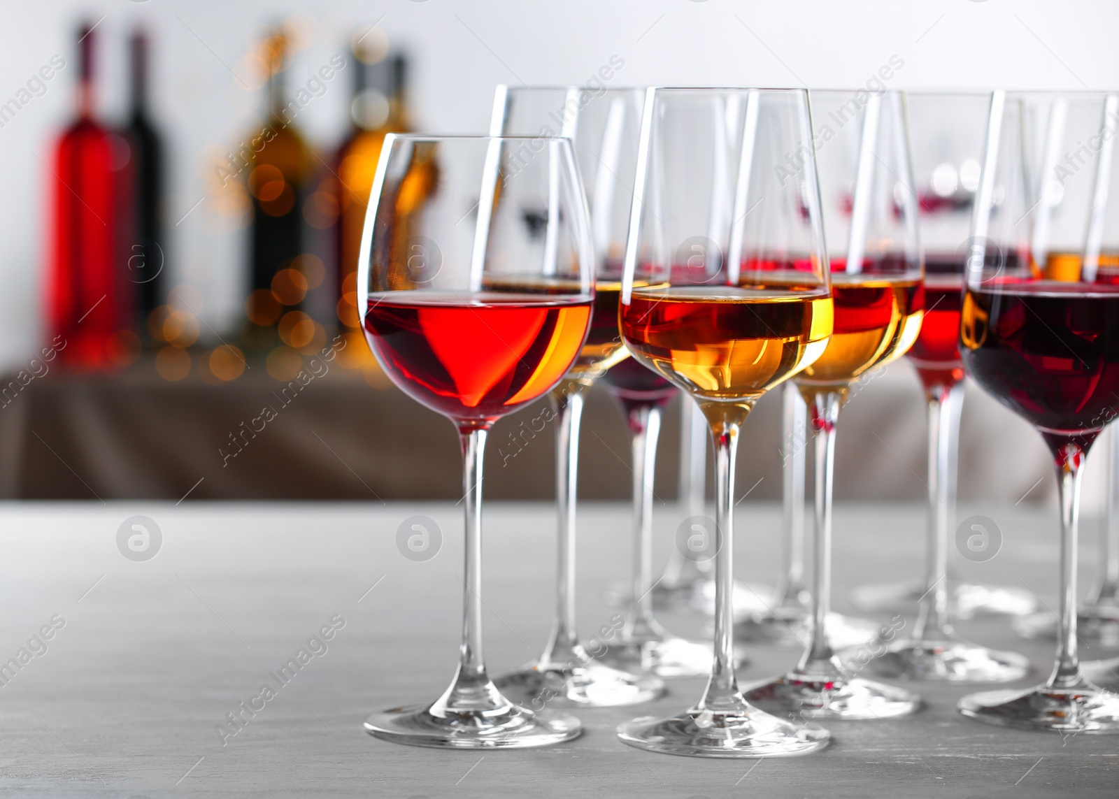 Photo of Glasses with different wines on table against blurred background. Space for text