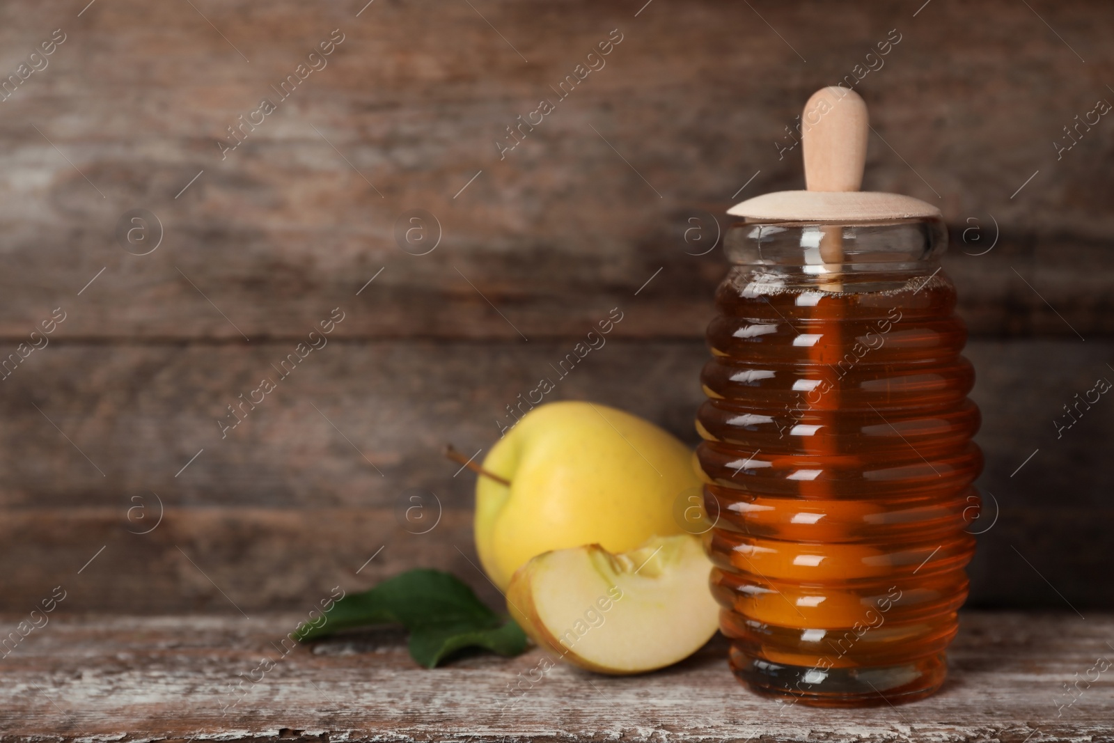 Photo of Jar of honey and apples on wooden table