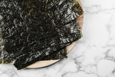 Photo of Dry nori sheets on white marble table, top view