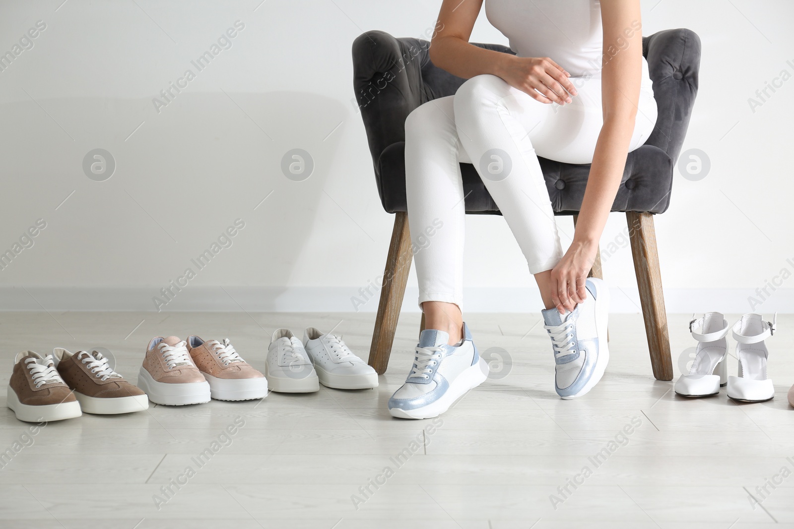 Photo of Young woman choosing shoes while sitting in armchair, closeup