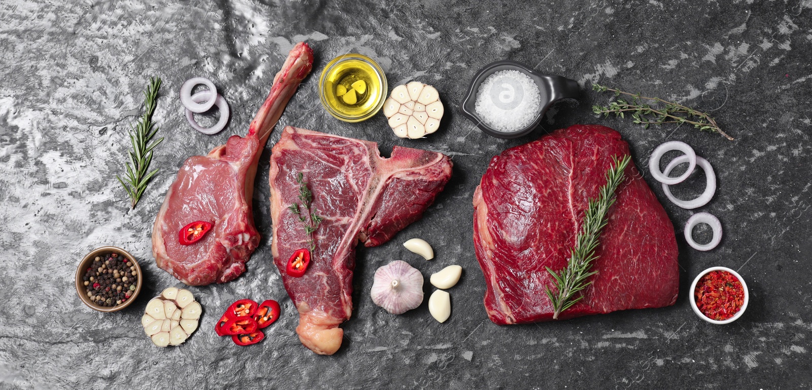 Photo of Fresh raw beef cuts and different spices on grey textured table, flat lay