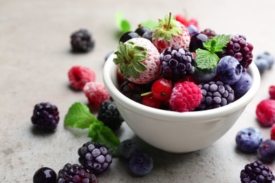 Photo of Mix of different frozen berries on grey table, closeup. Space for text