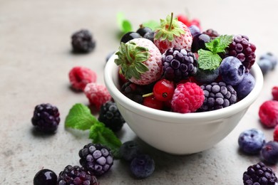 Mix of different frozen berries on grey table, closeup. Space for text