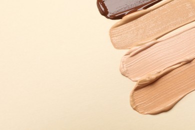 Photo of Samples of skin foundation on beige background, flat lay. Space for text