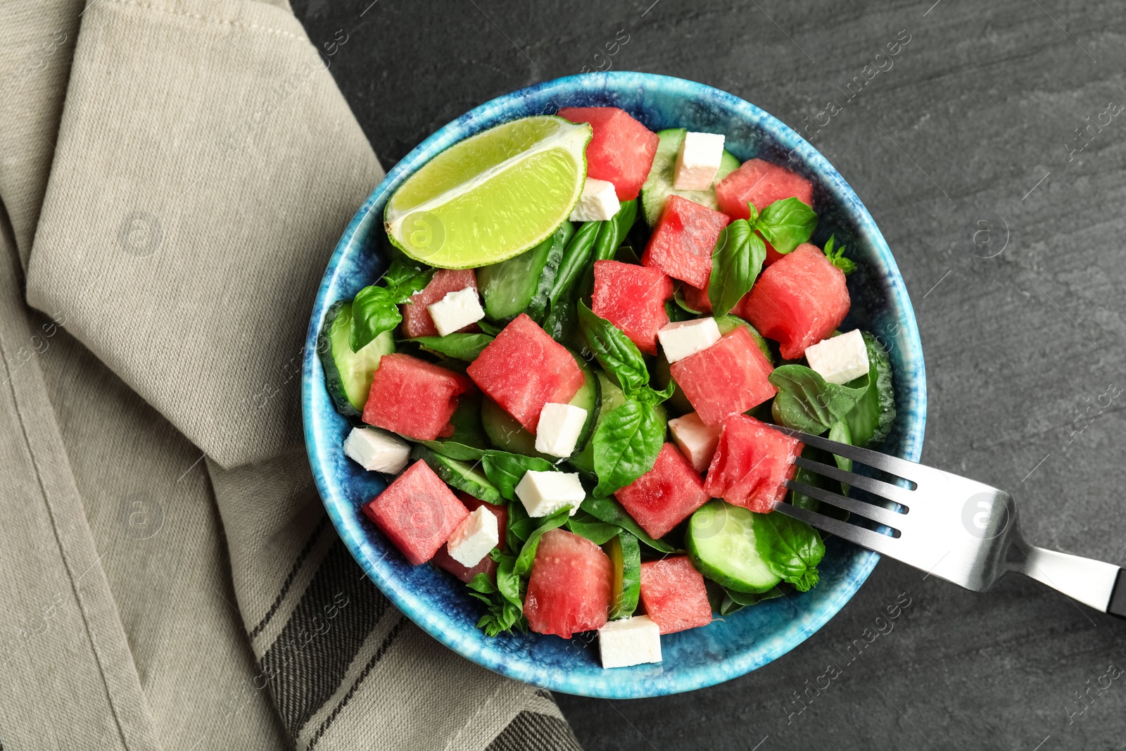 Photo of Delicious salad with watermelon served on black table, flat lay