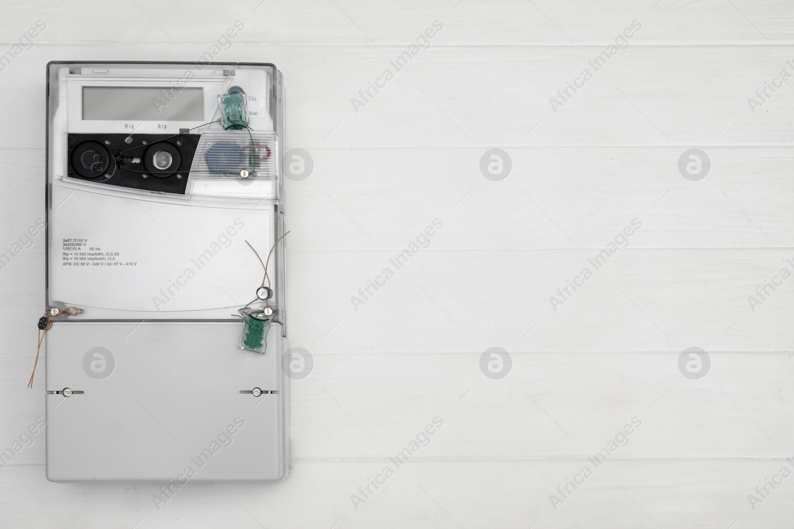 Photo of Electric meter on white wooden background, top view with space for text. Measuring device