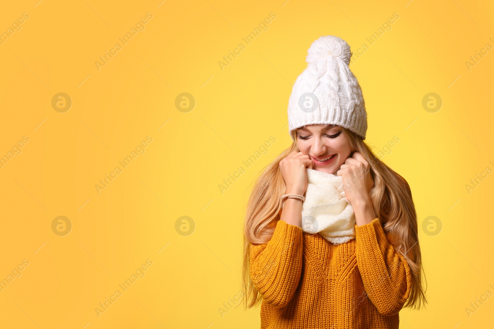Photo of Portrait of emotional young woman in stylish hat, sweater and scarf on color background, space for text. Winter atmosphere