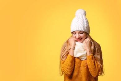 Photo of Portrait of emotional young woman in stylish hat, sweater and scarf on color background, space for text. Winter atmosphere