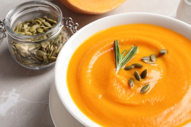 Bowl with tasty pumpkin soup served on table, closeup