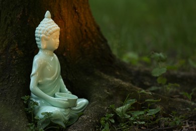 Decorative Buddha statue near tree outdoors, space for text