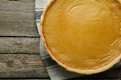 Photo of Delicious pumpkin pie on wooden table, top view. Space for text