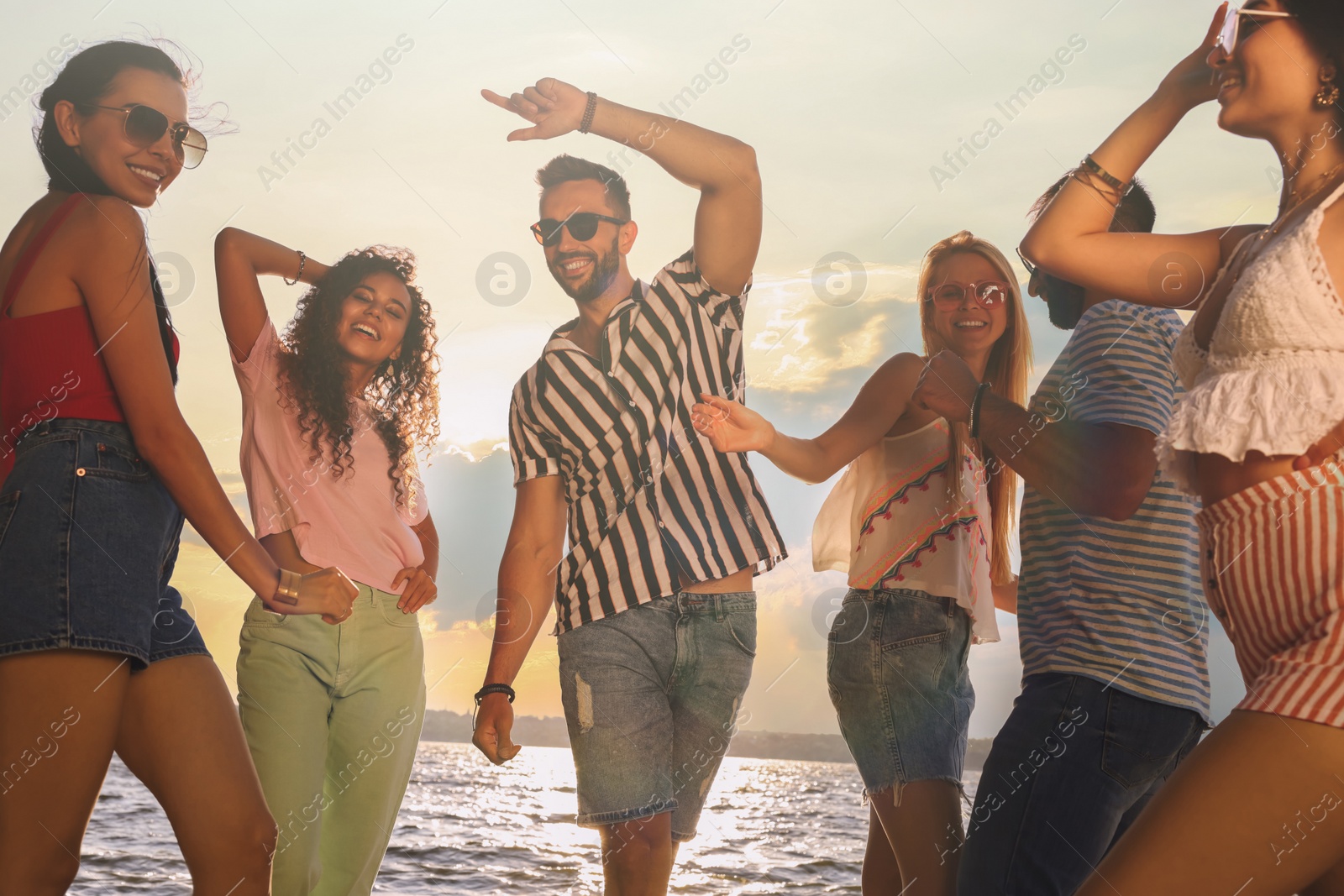 Photo of Group of friends having fun near river at summer party