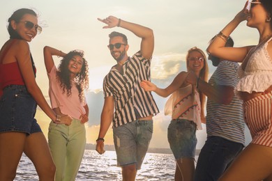 Photo of Group of friends having fun near river at summer party