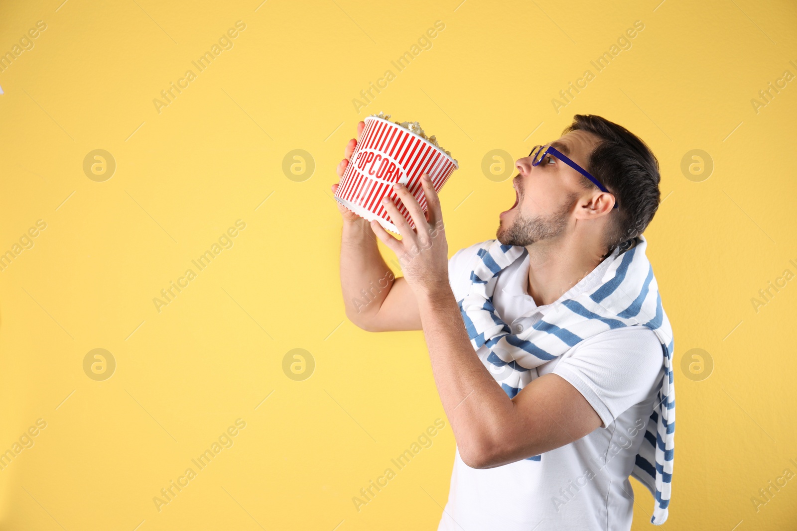 Photo of Emotional man with 3D glasses and tasty popcorn on color background. Space for text