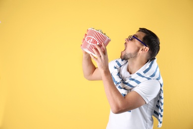 Emotional man with 3D glasses and tasty popcorn on color background. Space for text