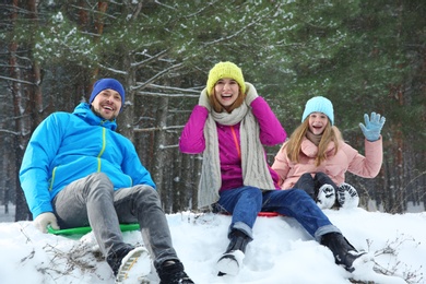 Happy family sledding in forest on snow day