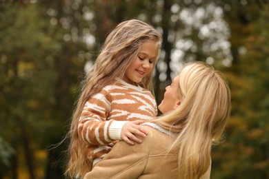 Happy mother spending time together with her daughter in autumn park