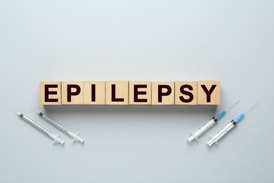 Photo of Word Epilepsy and syringes on light grey background, flat lay
