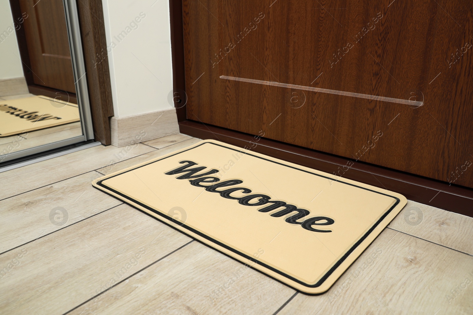 Photo of Beautiful beige doormat with word Welcome on floor near entrance