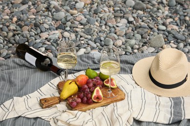 Photo of White wine and fresh fruits on picnic blanket outdoors