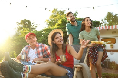 Photo of Happy friends resting near motorhome. Camping season