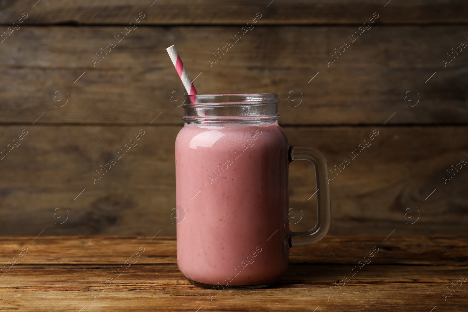 Photo of Mason jar with delicious berry smoothie on wooden table