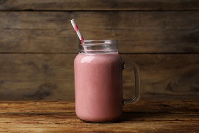 Photo of Mason jar with delicious berry smoothie on wooden table