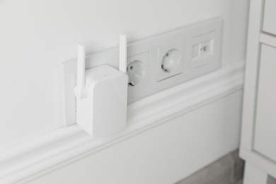 Wireless Wi-Fi repeater on white wall indoors