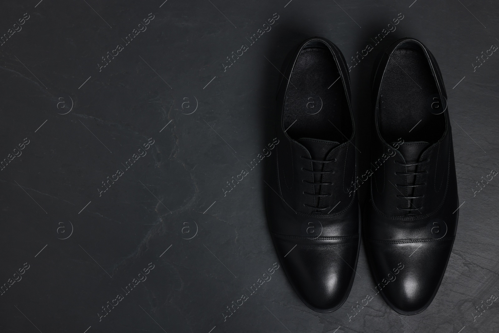 Photo of Pair of leather men shoes on black surface, top view. Space for text