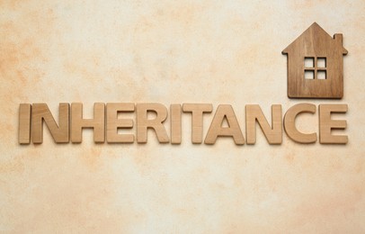 Photo of Word Inheritance made with wooden letters and house model on beige background, flat lay